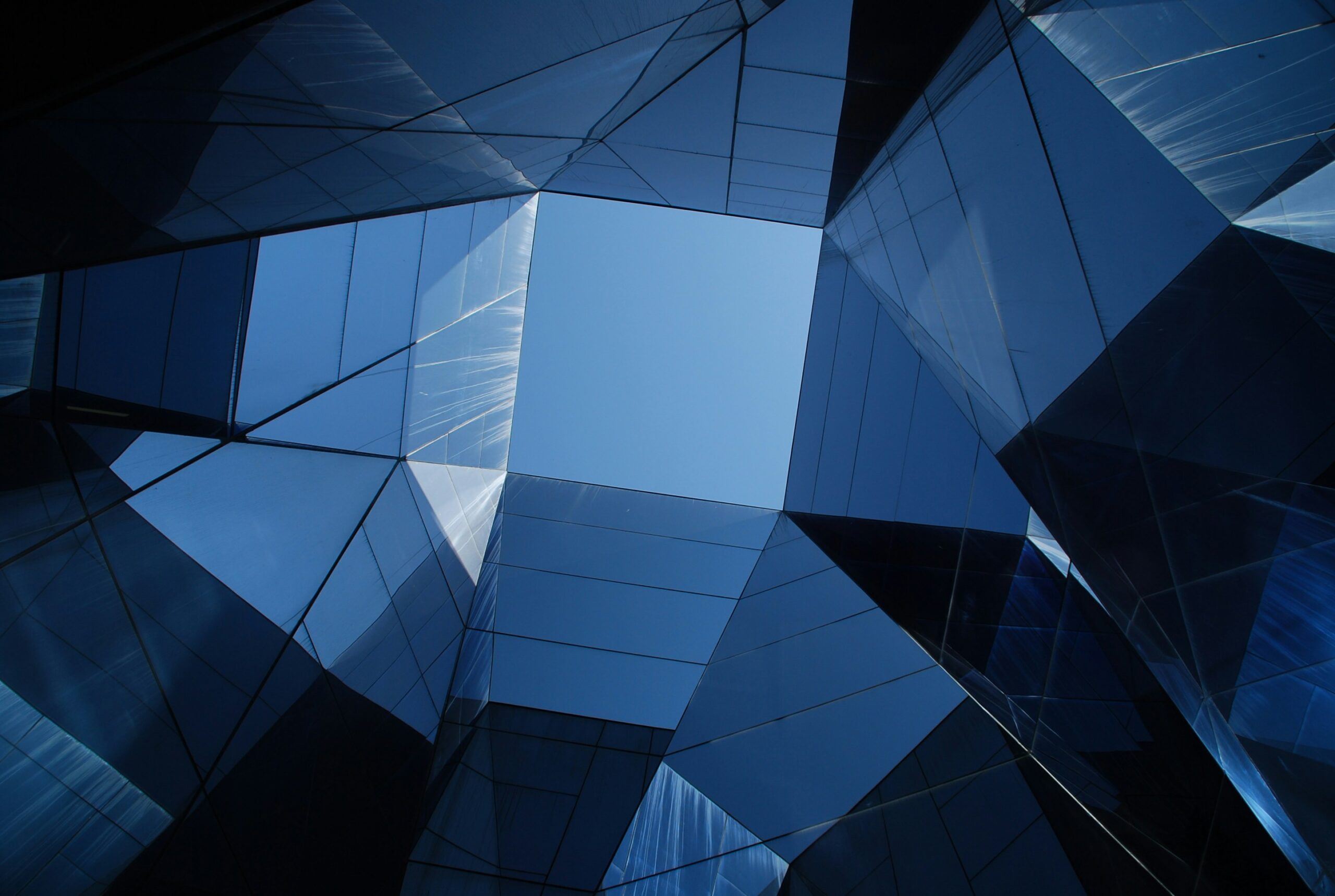 Blick durch das geometrische Glasdach eines Gebäudes, das den Himmel in einem faszinierenden Blau von BlueBranch GmbH zeigt.